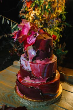 Zantedeschian çiçeğiyle süslenmiş üç katlı pasta, kırmızı yapraklar ve 