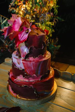 Zantedeschian çiçeğiyle süslenmiş üç katlı pasta, kırmızı yapraklar ve 