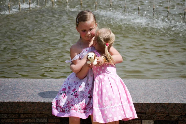 Dos Chicas Vestidos Rosa Abrazo Fuente —  Fotos de Stock