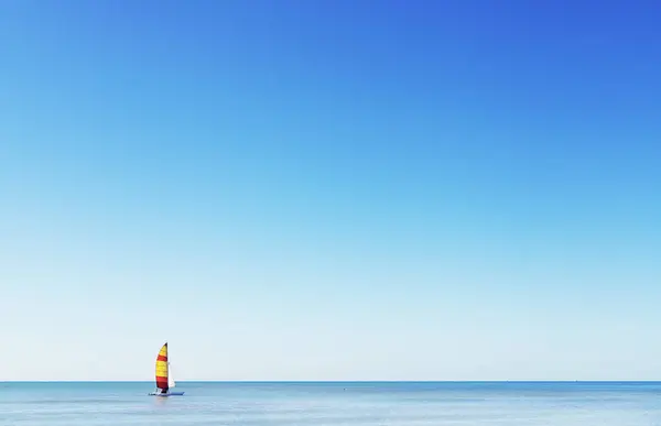 Beautiful sailboat in full sail on the Mediterranean sea ,yellow and red striped sail