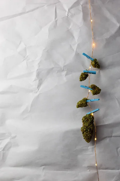 Marijuana clippé à des lumières à cordes sur fond de texture blanche — Photo