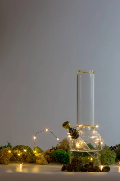 Bong en verre faiblement éclairé avec marijuana, lampes à cordes et mousse d'agai — Photo