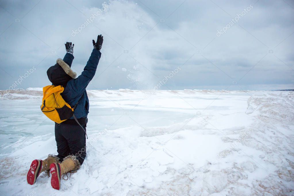 Woman throwing snow while kneeling on frozen wave