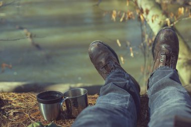 Kot pantolon deri ile adamın yanında iki kupalar çizmeler s üzerinde Nehri yakınında