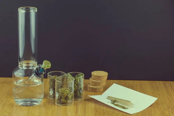Cam bong koni ile yanındaki Cam kaplarda tıbbi esrar haddeleme kağıtları ve eklem şeklinde