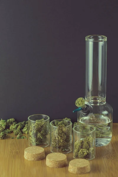 Marihuana in Glasbehältern mit Korkdeckeln und einer Glasbong — Stockfoto