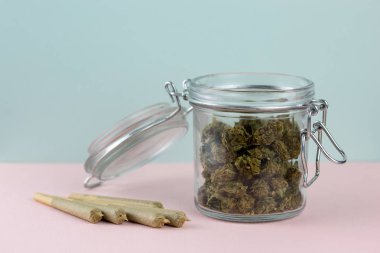 Pastel zemin üzerinde düzenlenmiş eklem yanındaki cam kavanoza esrar