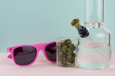 Pastel zemin üzerinde nargile ot cam kavanoz ve pembe güneş gözlüğü ile Paketli 