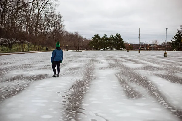 woman walking through a slush filled parking lot 