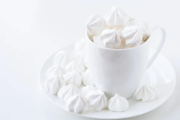 The side view of the white meringue in the white tea cup on the white plate — Stock Photo, Image