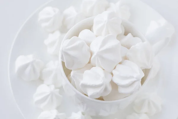 Beyaz çay Kupası ve beyaz plaka üzerinde beyaz merengue — Stok fotoğraf
