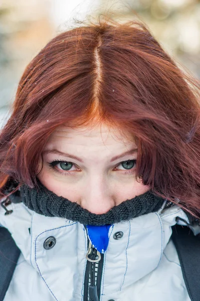 red-haired girl is cold and wrapped in a jacket