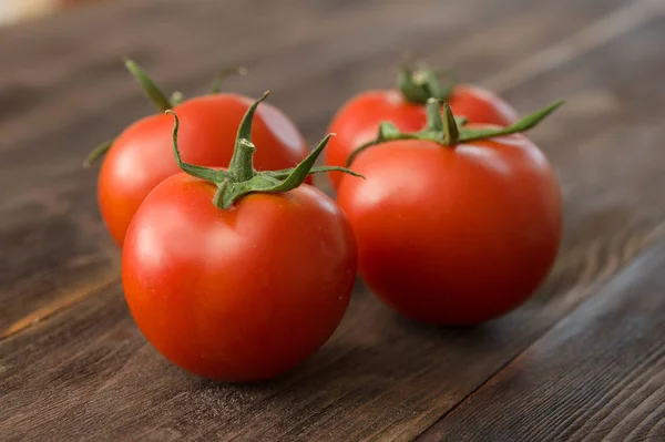 Juicy ripe tomatoes on a wooden table — Stock Photo, Image