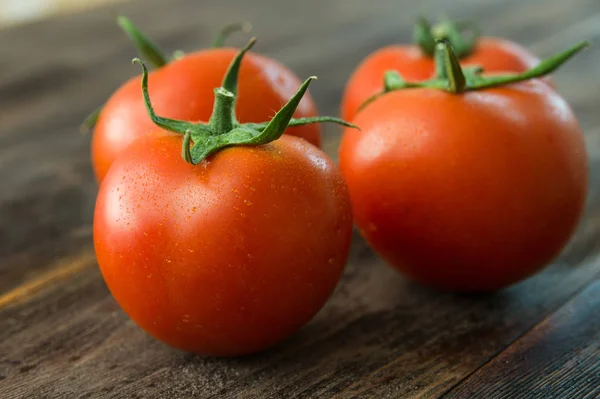 Soczyste i dojrzałe pomidory na drewnianym stole — Zdjęcie stockowe