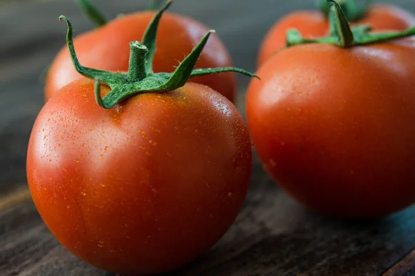 Soczyste i dojrzałe pomidory na drewnianym stole — Zdjęcie stockowe