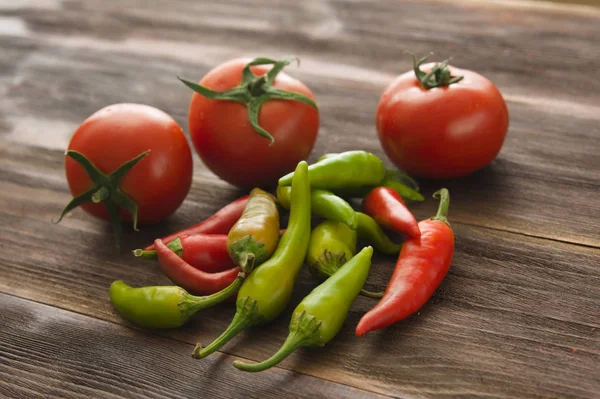 Ripe tomatoes, hot chili pepper on a wooden table — Stock Photo, Image