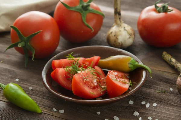 Ripe sliced tomatoes, hot chili peppers, garlic on a wooden tabl — Stock Photo, Image