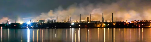 Sanayi kompleksi (Ukrayna 'da). Dinyeper nehri ve büyük metal bitki boruları. Atmosferde duman salınımı. Gece görünümü.