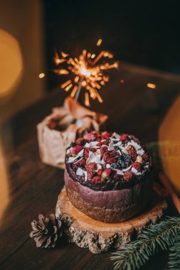 Ahşap arka planda çiçek desenli Noel pastası ve maytap.