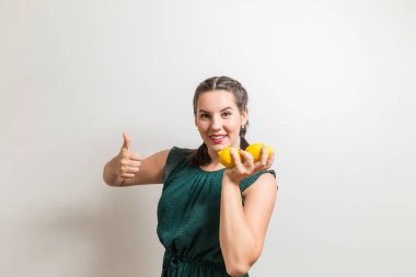 Güzel öğrenci kız başparmak yukarıya için limon ve meyve gösterir