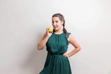 Güzel kız bir elma yeşil elbisenin içinde tutar.