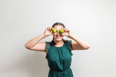 Gözlerinin üzerine limon meyve tutan mutlu sevimli kız gülümsüyor