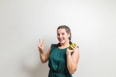 Neşeli kız meyve elinde tutarken barış gösterir