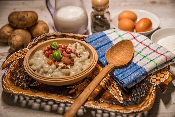 Slovak traditional dishes, potato gnocchi, bryndza, on wooden pancakes, potatoes, eggs. milk, sheep\'s cheese