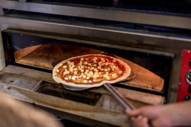 Bir şefin el pizza domates temel proshuto rukola ve rendelenmiş peynir hazırlanması, yakın çekim
