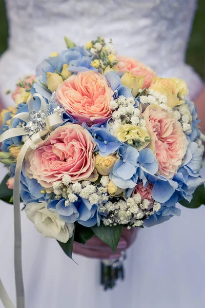 wedding bouquet, hands of bride holding a beautiful bouquet in hand, close-up of hands behind blurred background