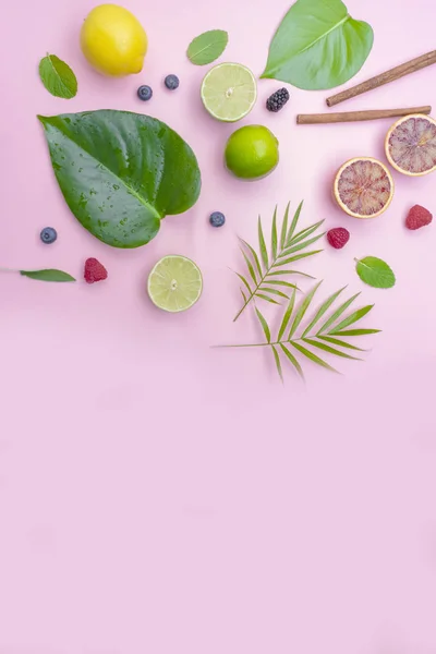 Tropikal meyve ve yaprakları pembe pastel bir arka plan üzerinde. Yukarıdan görünüm, daire, metin için yer