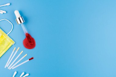 Tıbbi yüz maskesi, elektronik termometre ve mavi arka planda lastik eldivenli kan testi. Düz yatıyordu. Boşluğu kopyala.