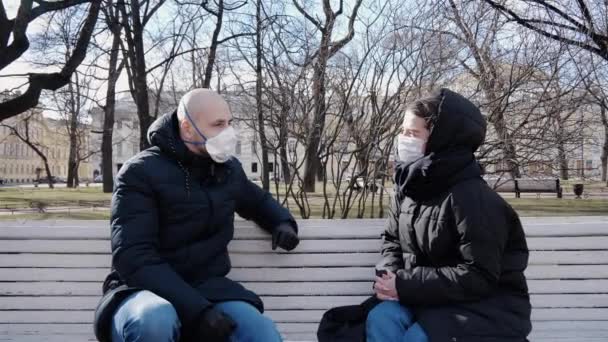 隔離された患者コロナウイルスのマスクの男と女の子は距離を置かずに外に出て公園のベンチに座って — ストック動画