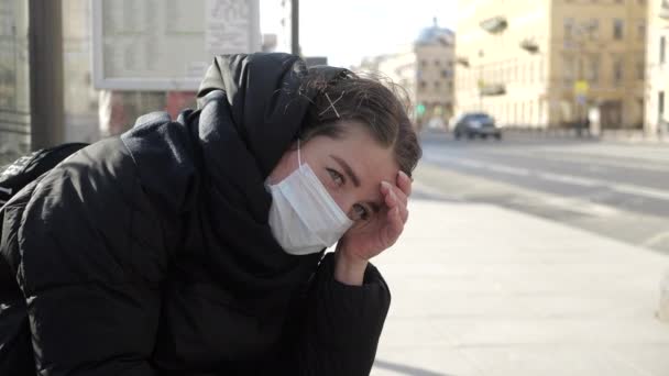 感染した患者のためのマスクの少女は絶望と悲しみで公共交通機関の停留所でバスを待っています — ストック動画