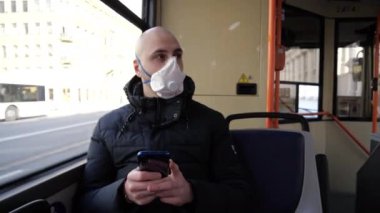 Coronavirus 'a yakalanmış orta yaşlı bir adam ıssız bir şehrin penceresinde oturan bir otobüse biniyor ve telefonuna bir mesaj yazıyor.