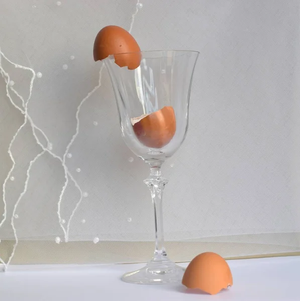 Egg shell in a transparent wine glass on white background.