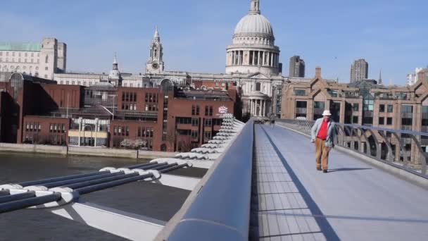 Man cammina sul Millenium Bridge nel centro di Londra in una bella giornata nel marzo 2020 . — Video Stock