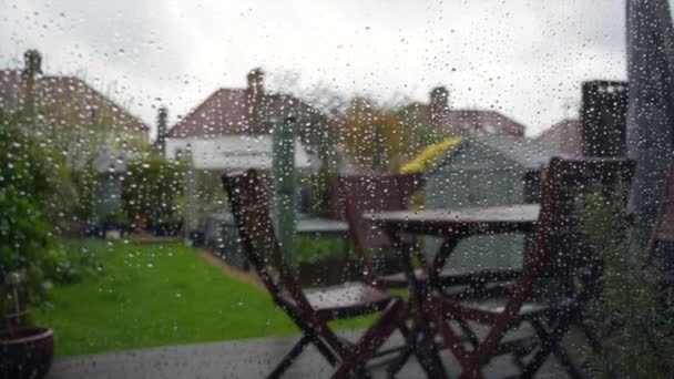 Dešťové kapky na sklo a zahradu s domy v Londýně za špatného počasí. — Stock video