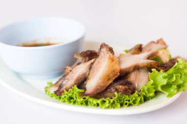 Boyun domuz eti ızgara marul ve beyaz zemin üzerine sos ile çanak hizmet