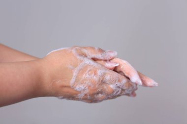 Gri arka planda sabunla kadın ellerini yıkamak.