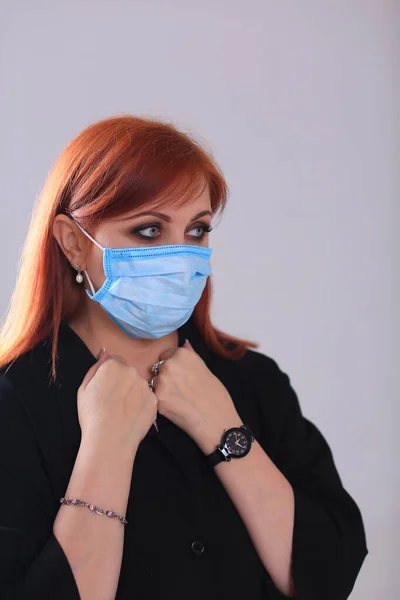 Siyah elbiseli, gri arka planda mavi maskeli kızıl saçlı bir kızın portresi.