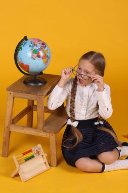 Kafkasyalı birinci sınıf öğrencisi, sarı arka planda uzun örgülü, Afrika, Avrupa ve Amerika 'ya benzeyen bir küreye sahip.