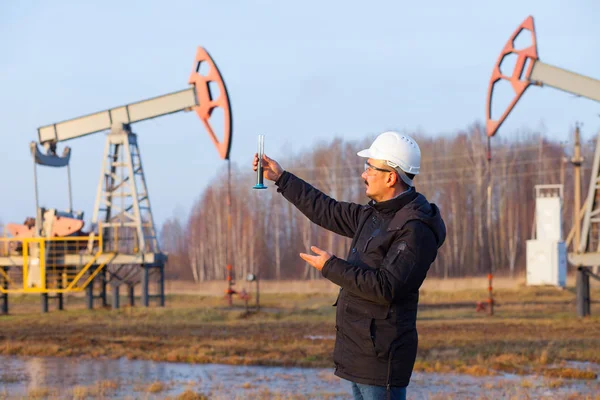 Engineer in a white helmet on an oil rig with a tablet. Oil production in Russia, Republic of Bashkortostan. Quality control. Oil production schedule