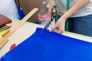 Terzi çizimden bir parça kumaş kesiyor..