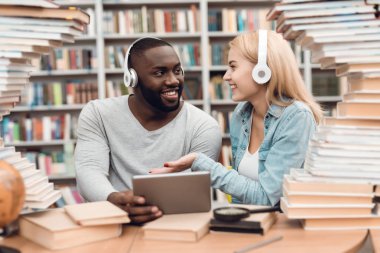 Etnik Afrikalı-Amerikalı adam ve Kütüphane masada oturan ve tablet kullanma beyaz kız