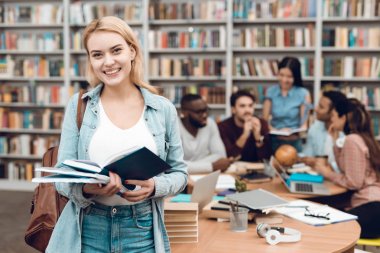 Etnik çok kültürlü öğrenci Kitaplığı ' nda masada beyaz kız kitap okuma oturma grubu