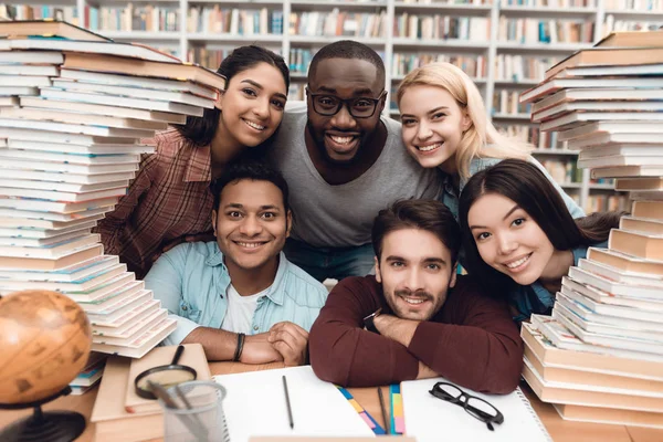 六族裔学生 非洲裔美国人和白色坐在桌边与书在图书馆里 — 图库照片