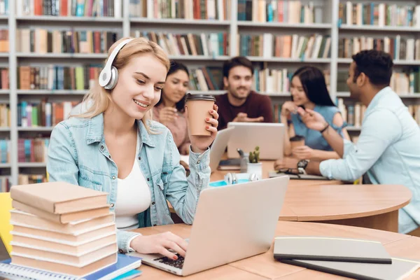 一群多文化的学生坐在图书馆的桌子上 白人女孩在笔记本电脑上使用耳机 — 图库照片
