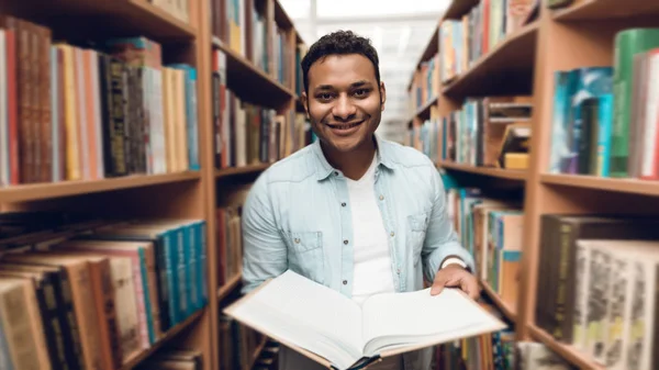 Ethnic indian mixed race student in library surrounded by books