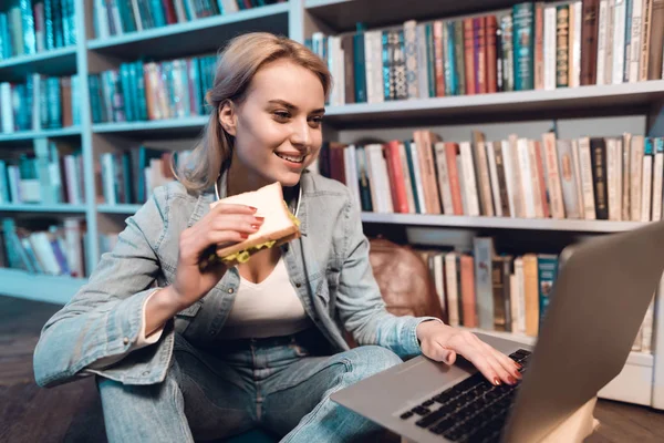 White Girl Sitting Bookshelves Library Eating Sandwich Using Laptop — Stock Photo, Image